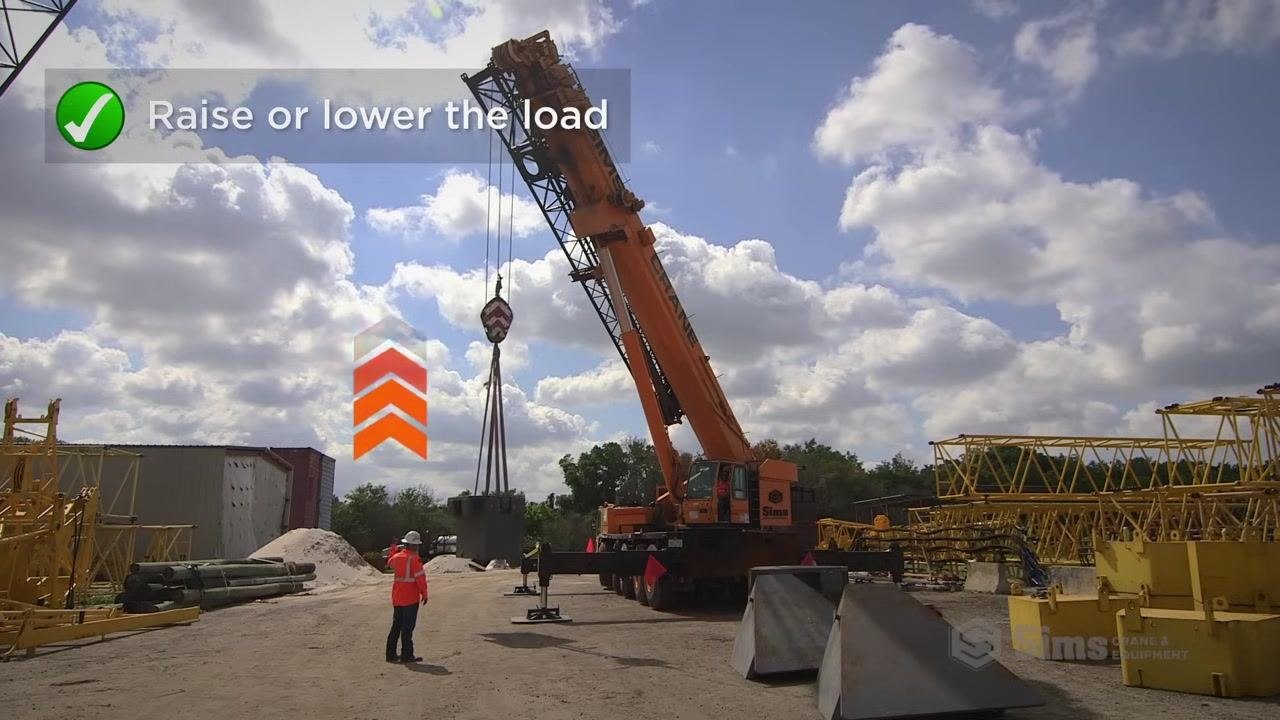 Signal person with arm extended to the side moving the hand horizontally, crane and suspended load visible in the background.