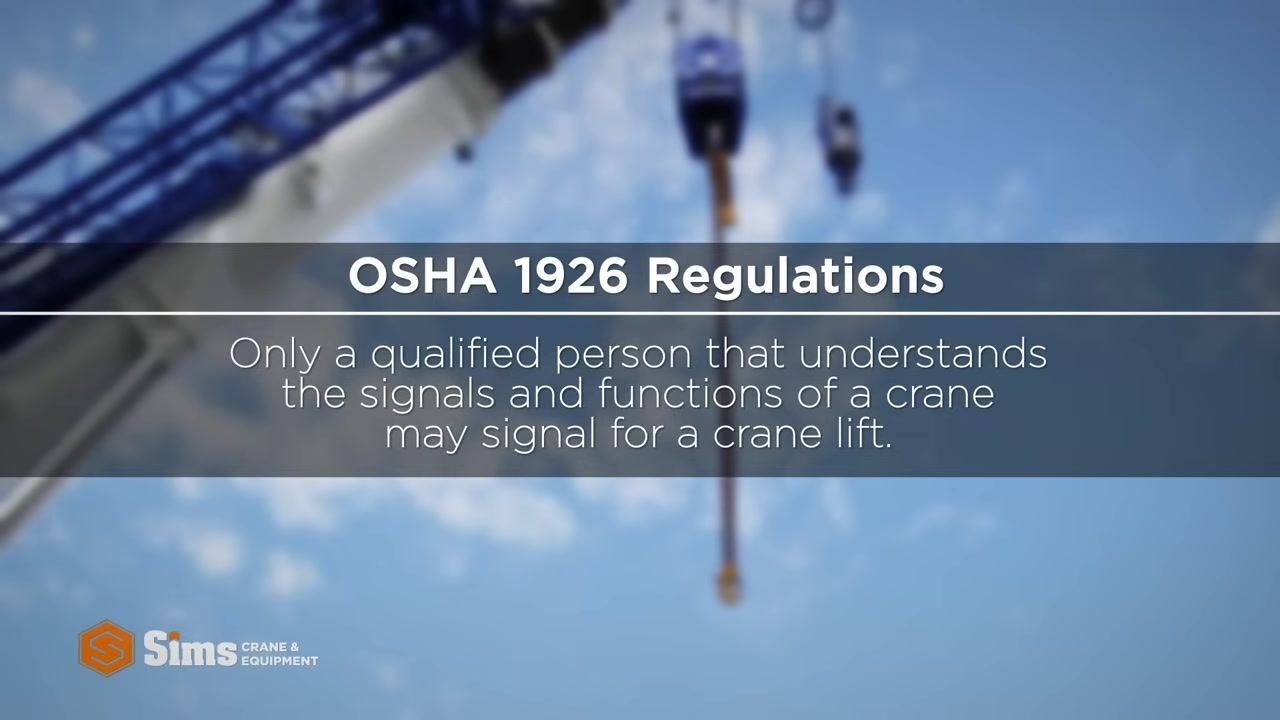 Safety instructor in high-visibility vest and hard hat next to a warning sign reading: "Every qualified signal person must know and understand basic hand signals before flagging for a crane operation."