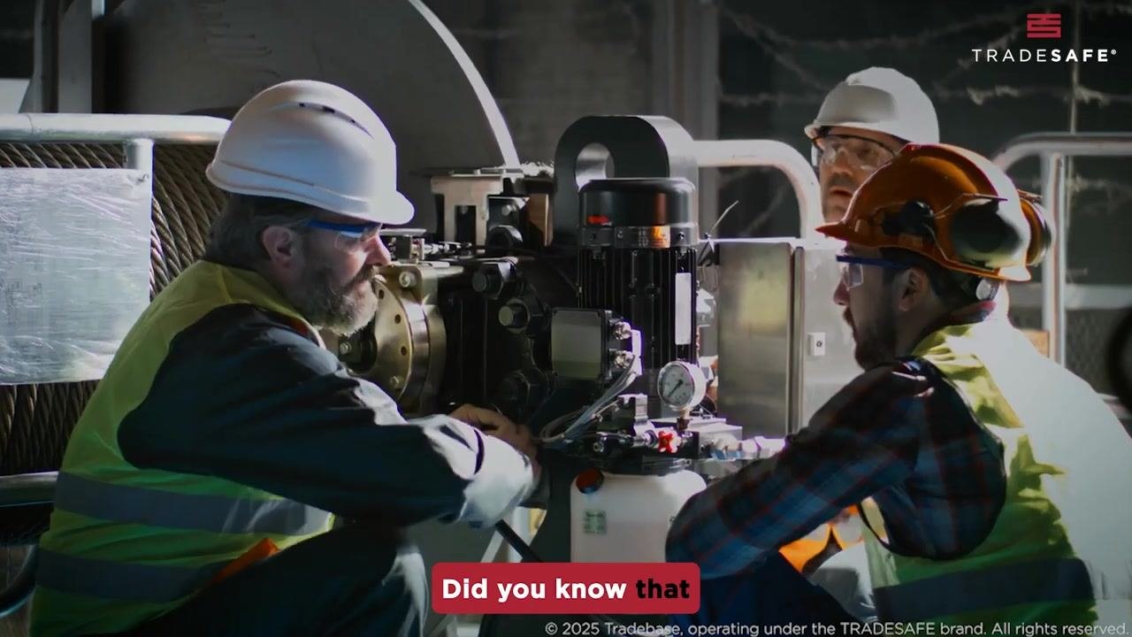 Three workers in safety gear discuss industrial machinery in a facility.