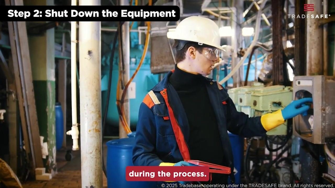 A close-up of a hand turning a red valve on industrial piping.