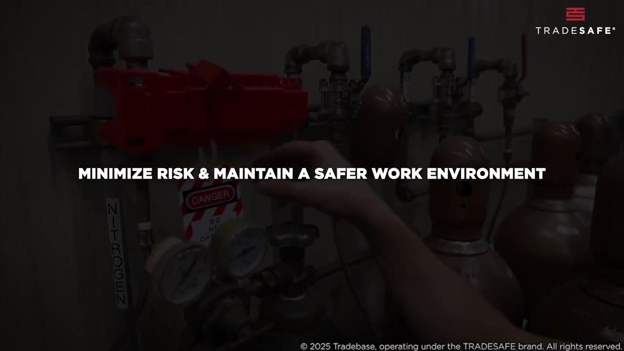 A worker's hands attach a "DANGER" tag to a red lockout device on a pipe.
