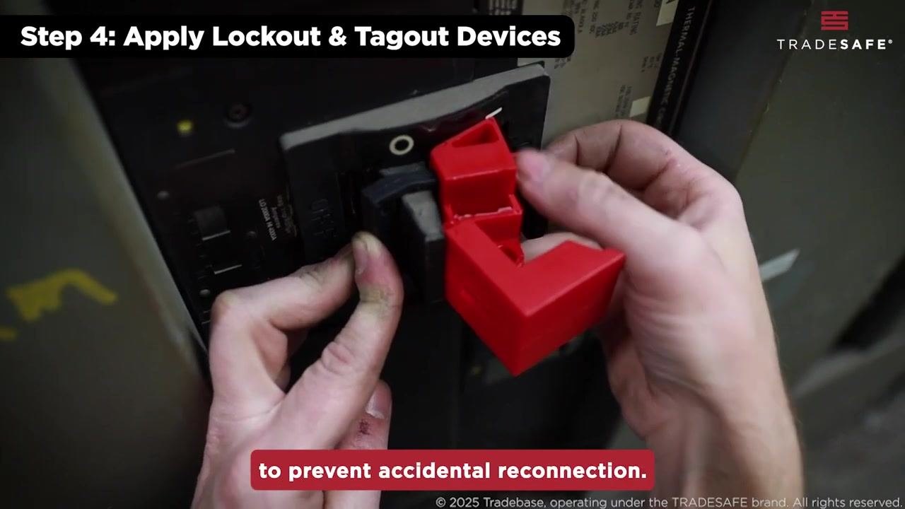 A hand holds a "DANGER" lockout tag, preparing to attach it to a red lockout device.