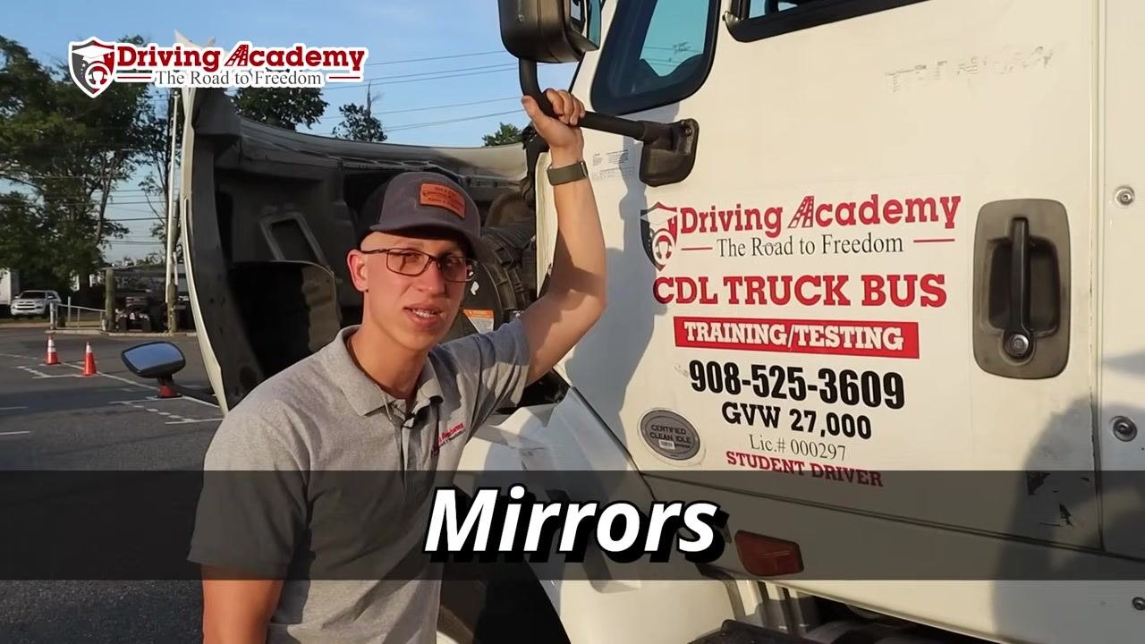 Instructor pointing at the exterior lights on the truck cab next to the door.