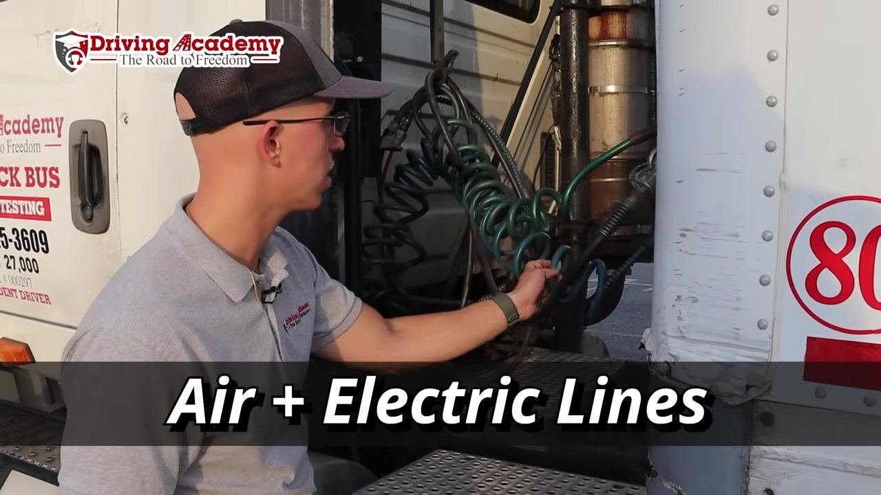 Instructor pointing at the air and electric lines connecting tractor and trailer.
