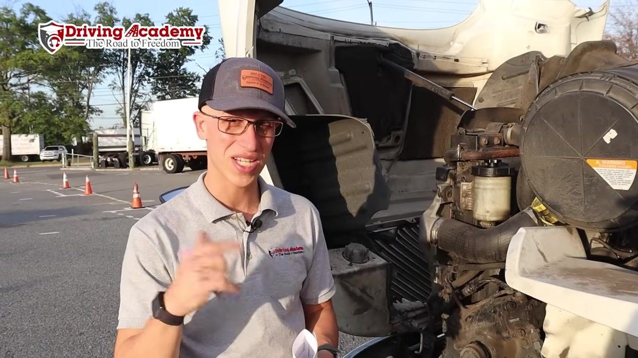 Instructor's hand demonstrating how to check the oil dipstick.