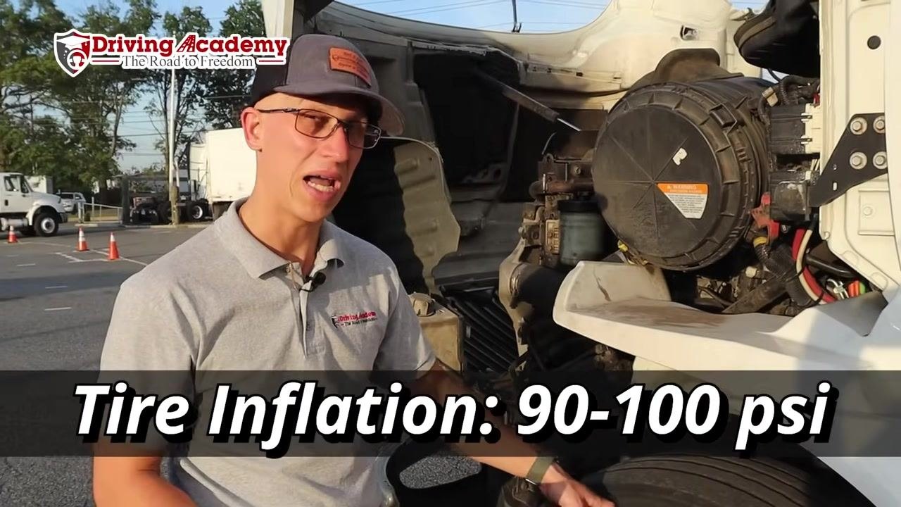 Instructor standing next to the tire explaining the inflation check using a tire gauge.