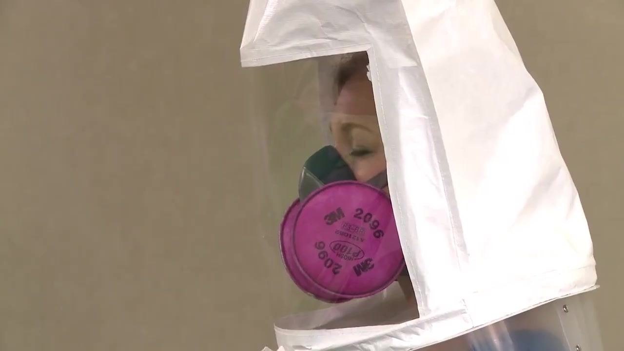 Close-up of a test subject wearing a respirator and fit test hood, indicating a successful fit.