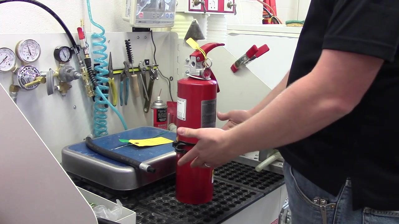 A person preparing to remove the zip tie from the fire extinguisher after completing the fluffing procedure.