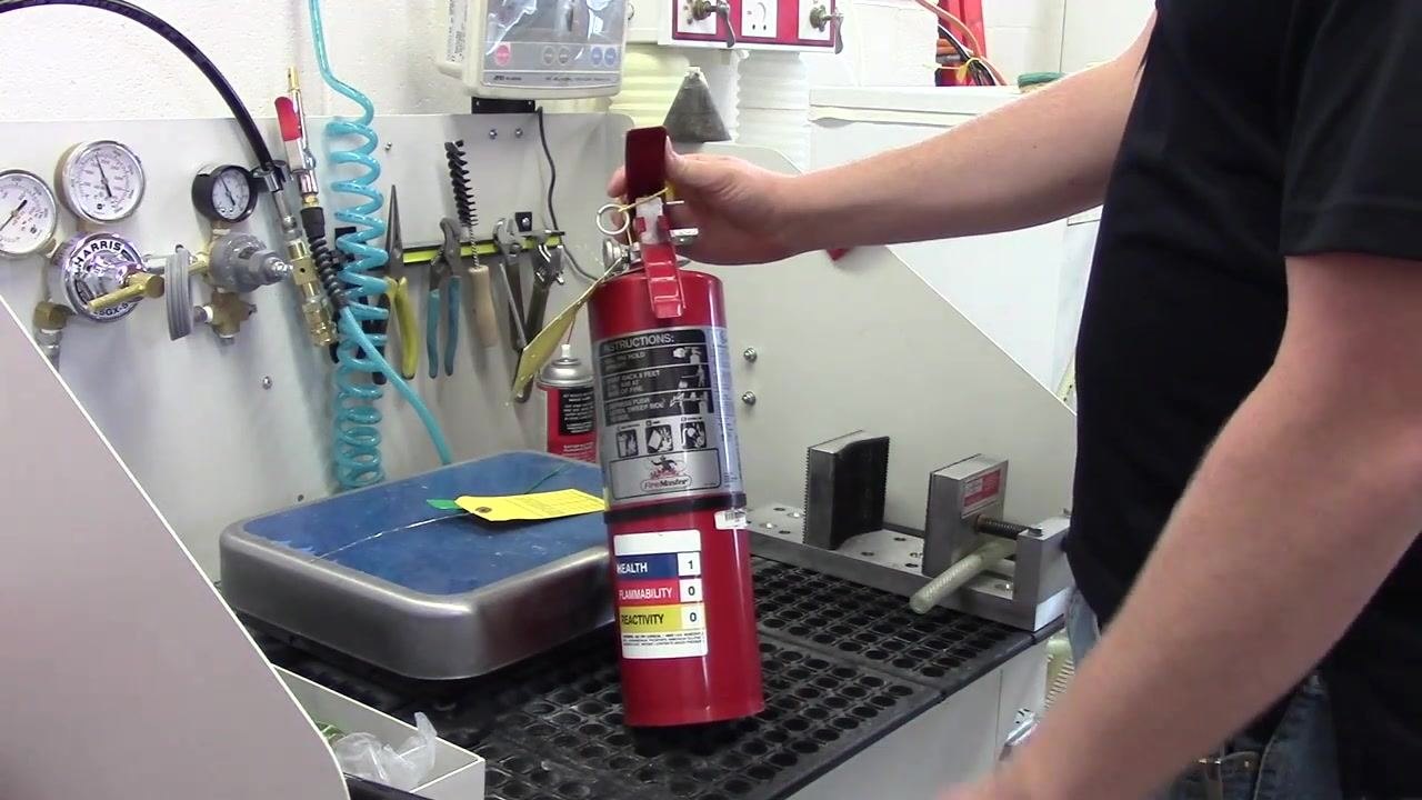 A person visually inspecting the fire extinguisher for dents, deformities, or corrosion.
