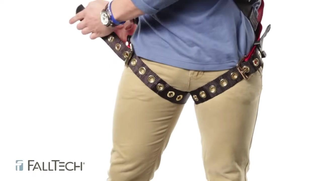 Person fastening a tongue buckle leg strap, demonstrating correct tightness by fitting two to three fingers between the strap and the leg