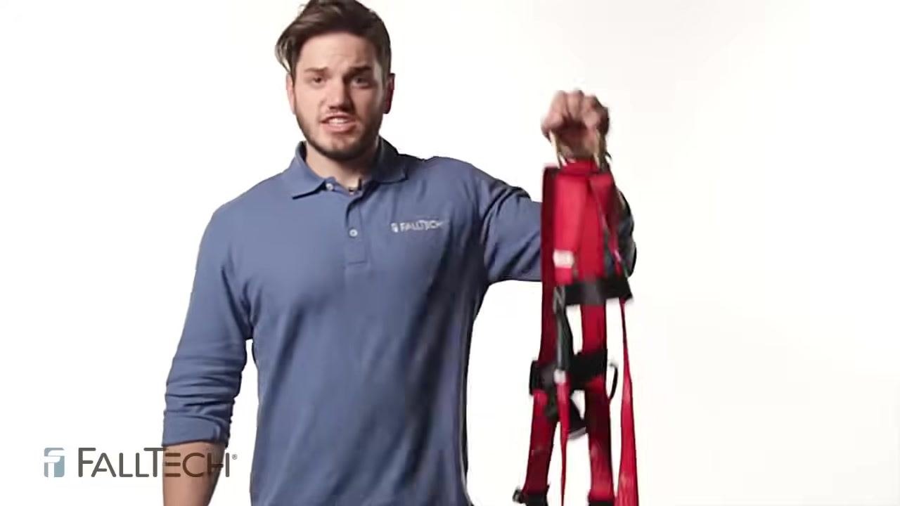 Person holding a red harness by the back dorsal D-ring, demonstrating how to raise and shake it