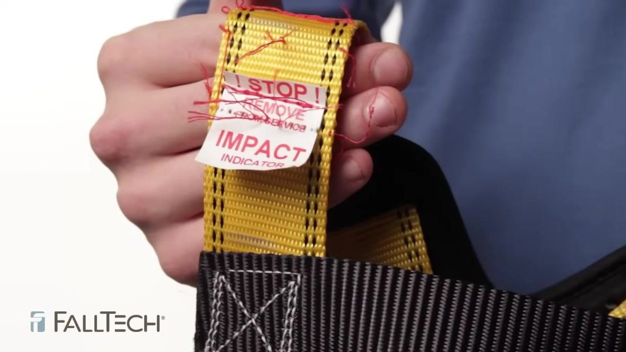 Close-up of yellow webbing labeled "STOP! REMOVE FROM SERVICE IMPACT INDICATOR" with visible red threads, showing an exposed impact indicator