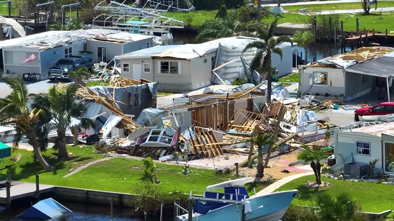 Storm damage seen from above, with debris scattered across a residential street and rooftops torn away, showing the scale of disruption an alert system must account for.