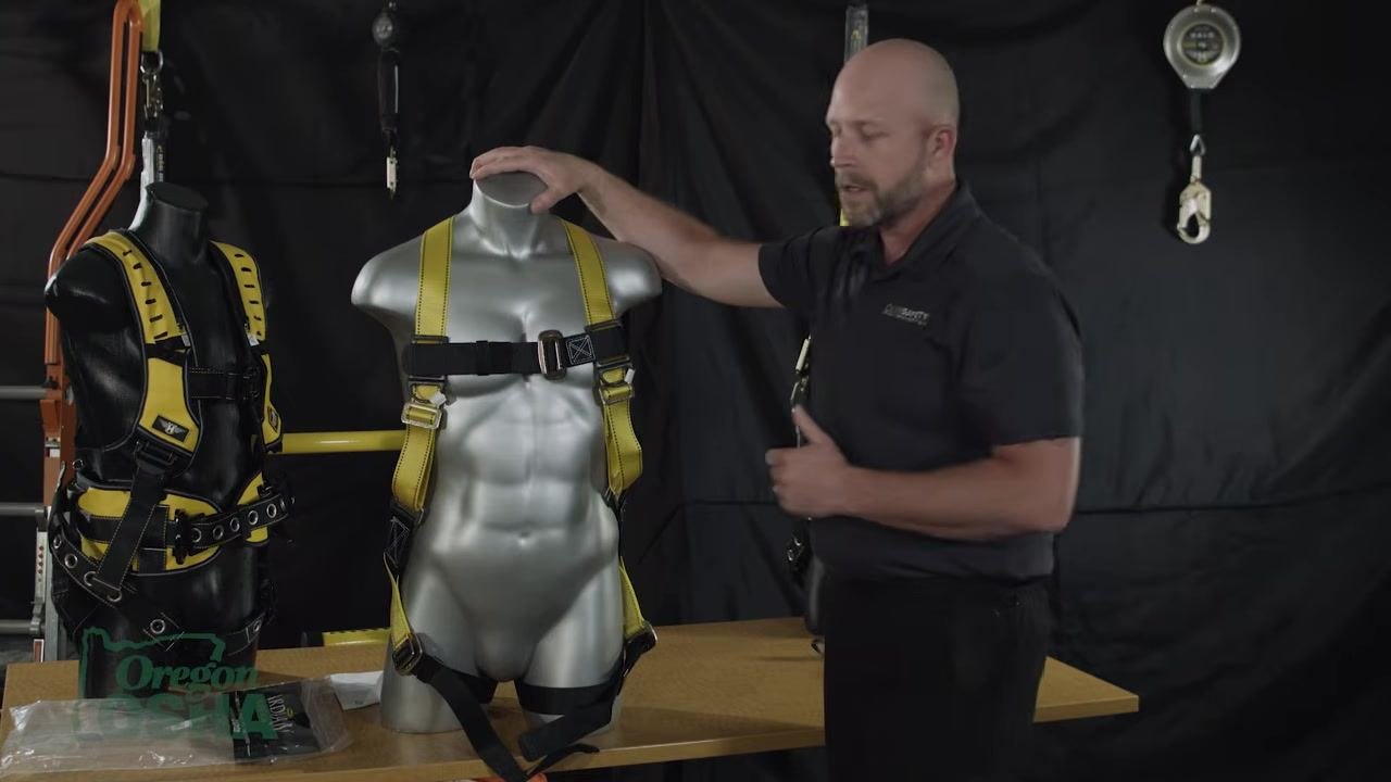 Placing a hand on a mannequin's shoulder, emphasizing symmetrical harness adjustment