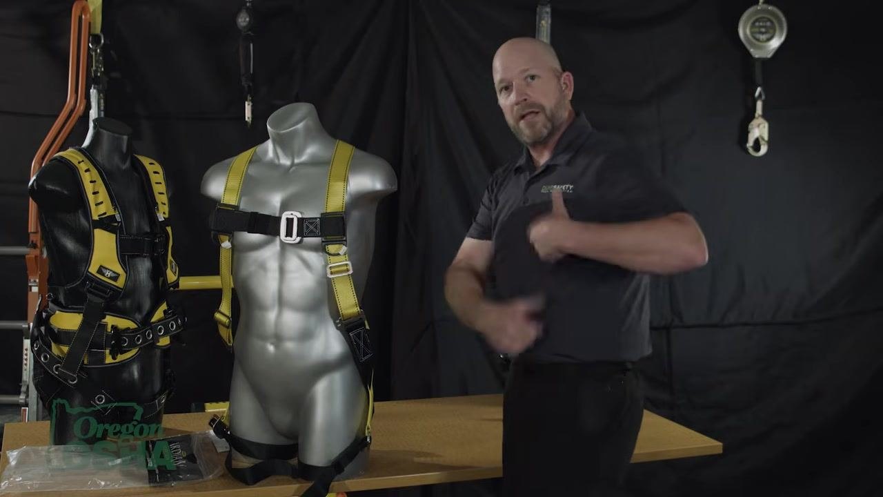 Gesturing to the harness on a mannequin, explaining strap adjustment and possible movement of the chest strap during tightening