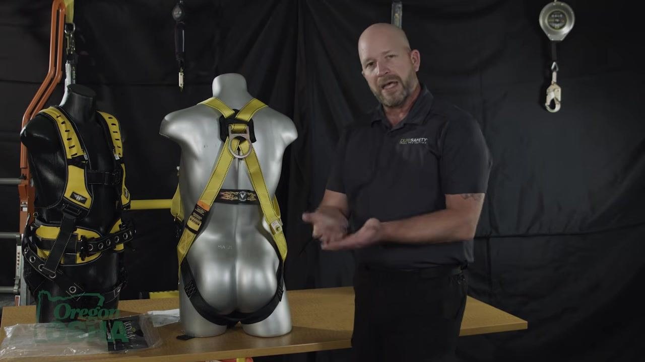 Gesturing with hands in front of a mannequin, explaining how the sub-pelvic strap creates a seat during a fall