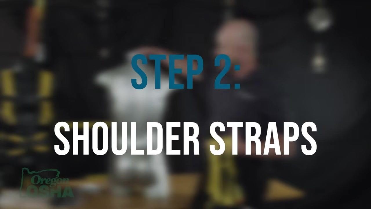 Instructor placing the harness over a mannequin's shoulders, demonstrating correct positioning