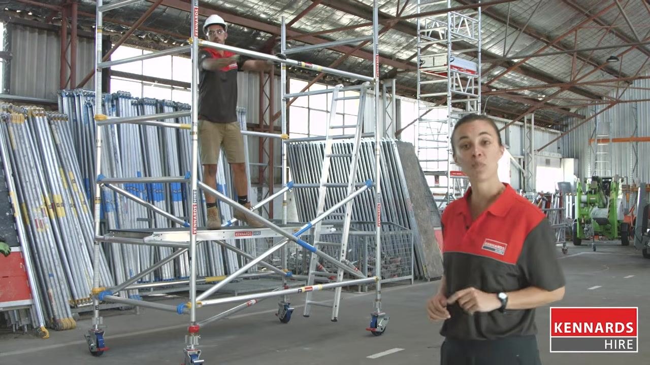 Worker kneeling to secure the ladder inside the scaffold
