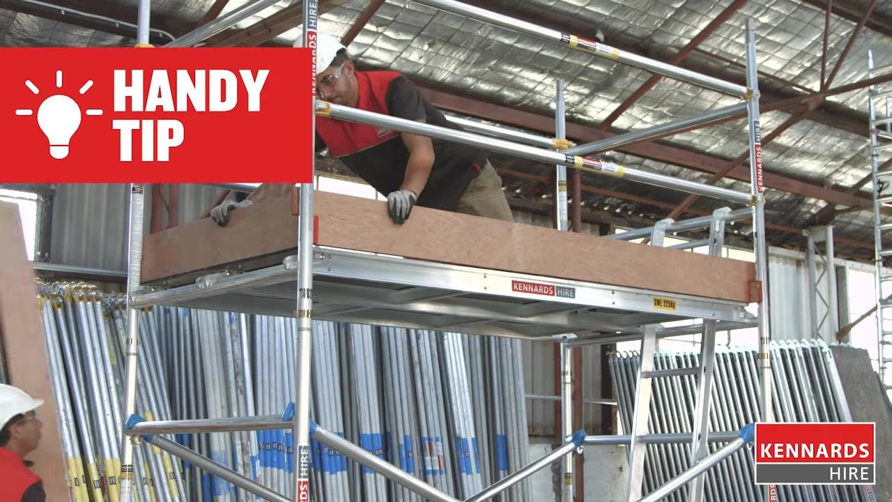 Worker installing the hatch deck on the upper platform, with a handy tip displayed