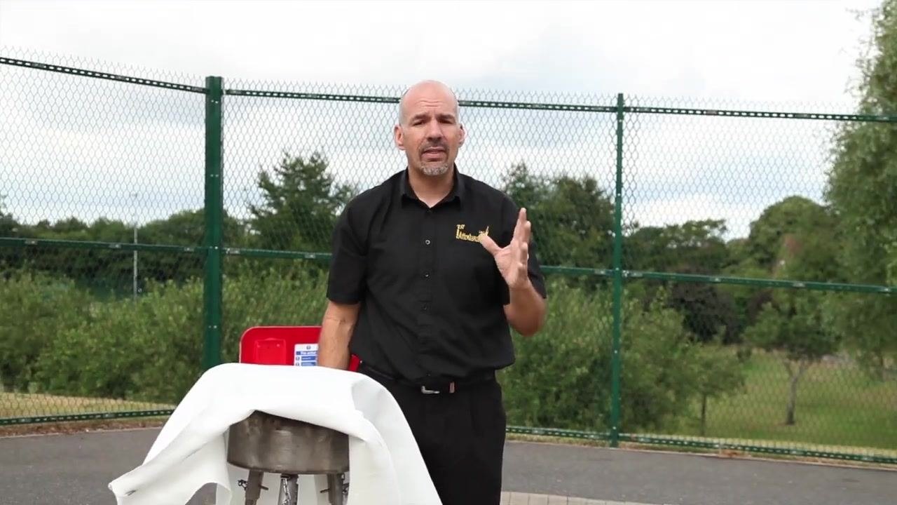 Person standing next to a covered pan, emphasizing the importance of safety and calling emergency services if needed.