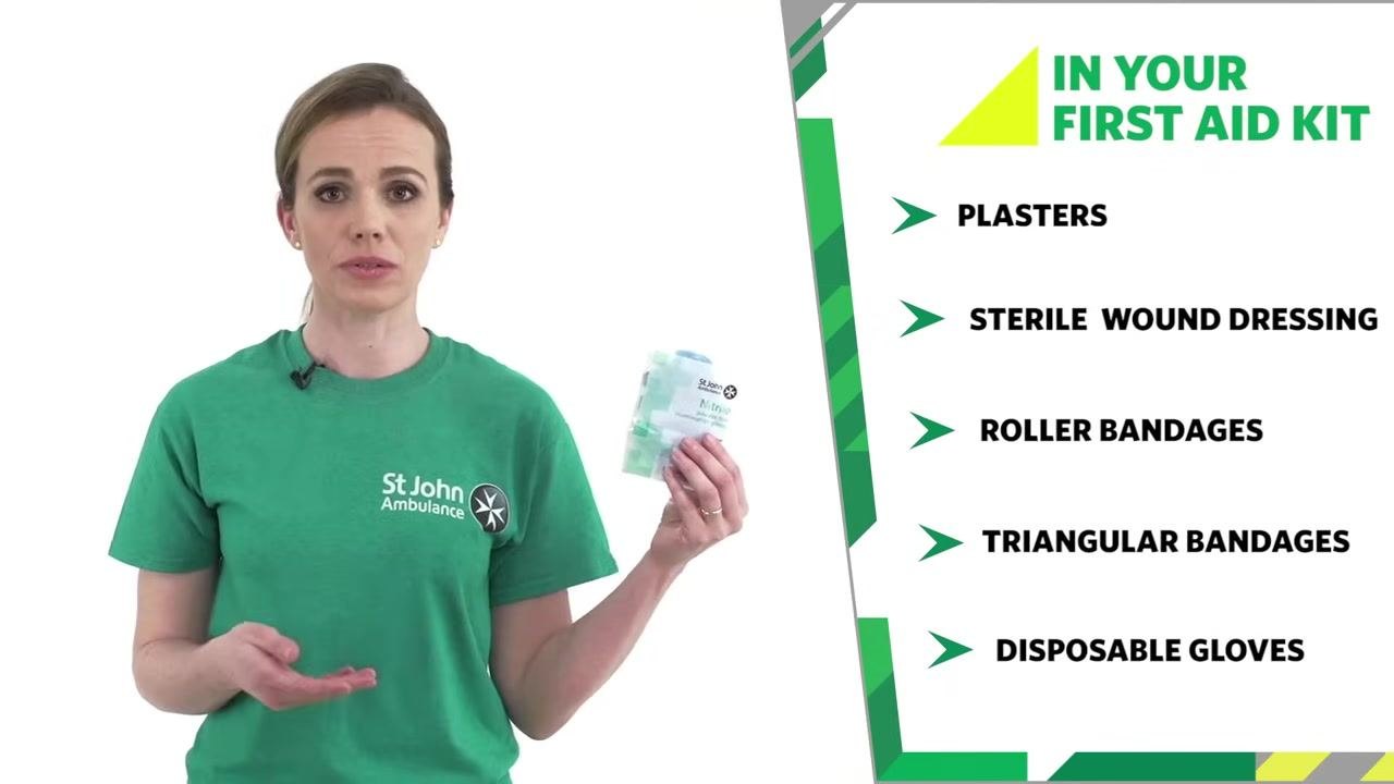 Trainer holding a wound dressing, with an on-screen list titled "IN YOUR FIRST AID KIT": Plasters, Sterile Wound Dressing, Roller Bandages, Triangular Bandages, Disposable Gloves