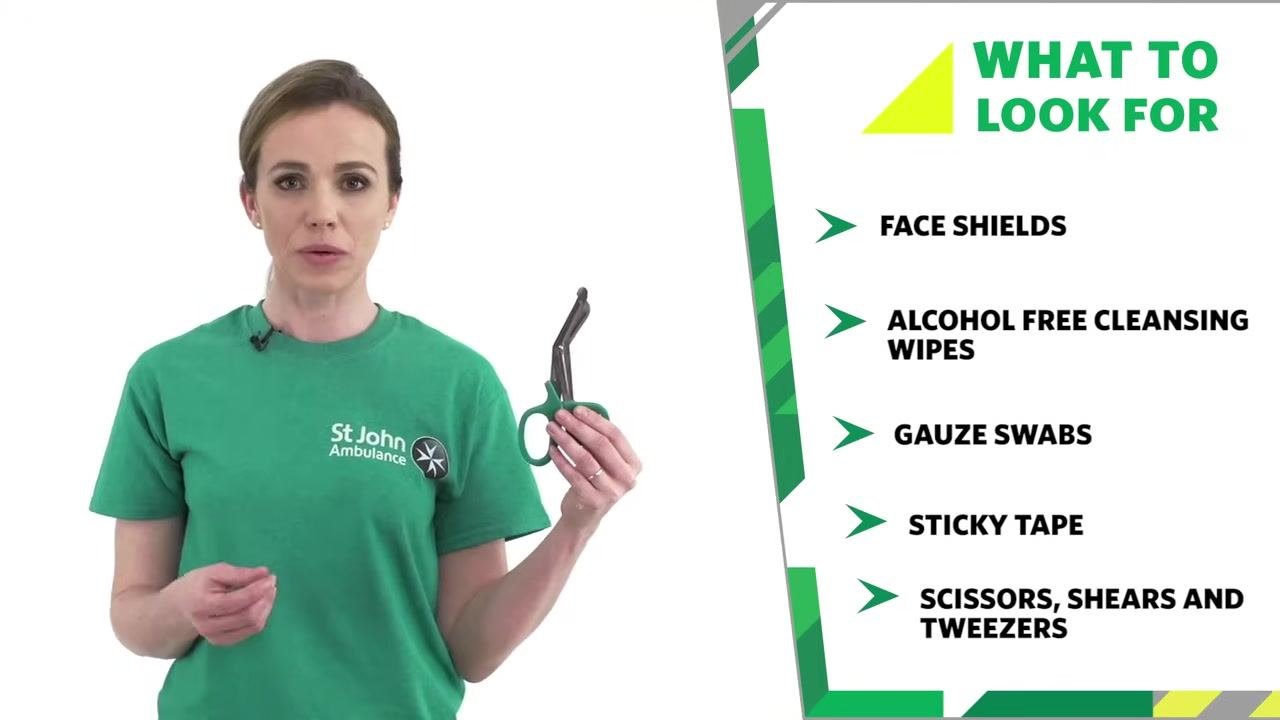 Trainer holding scissors, with an on-screen list titled "WHAT TO LOOK FOR": Face Shields, Alcohol Free Cleansing Wipes, Gauze Swabs, Sticky Tape, Scissors, Shears and Tweezers