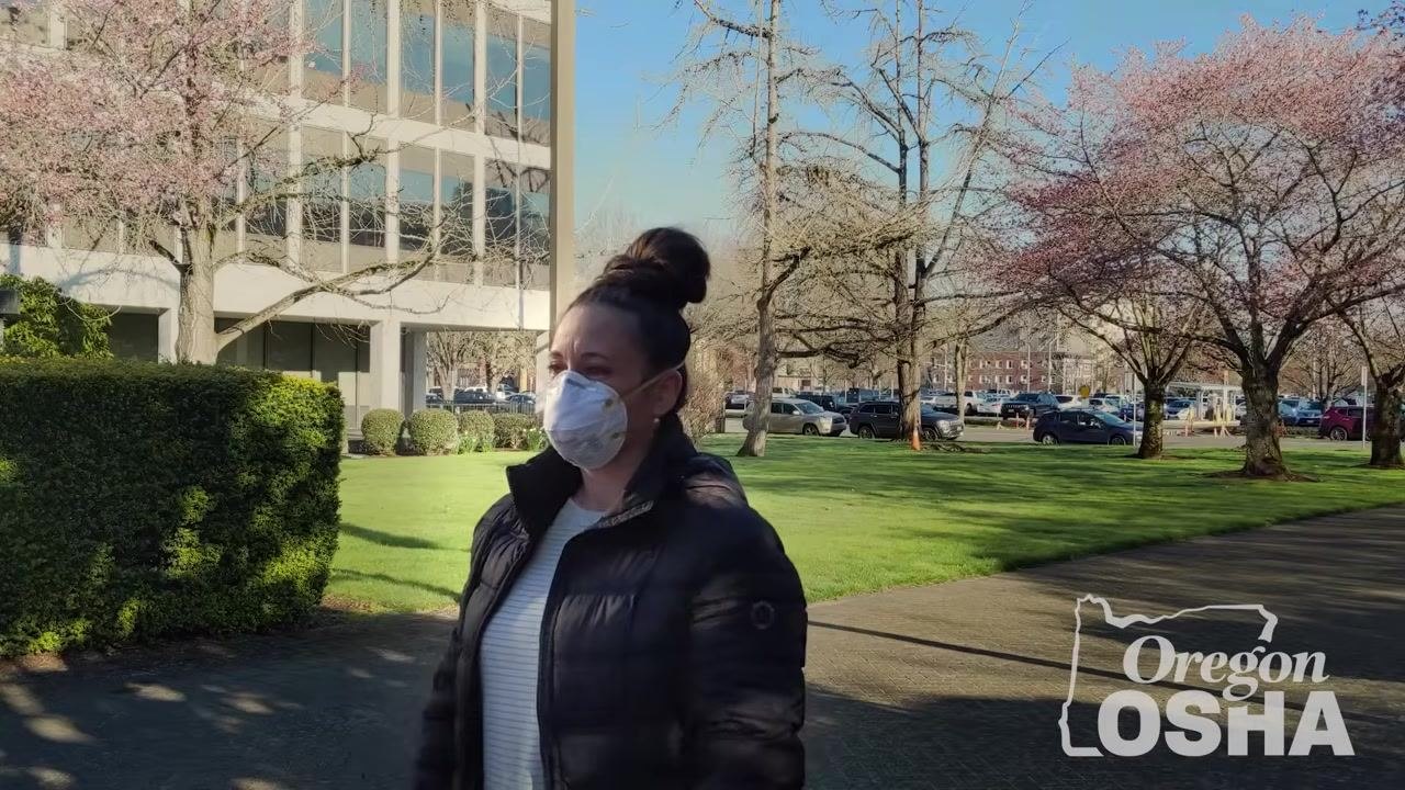 Person performing a seal check indoors by covering the N95 mask with both hands