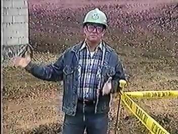 Two workers, one in a green hard hat and one in a pink hard hat, discussing safety procedures at the construction site.