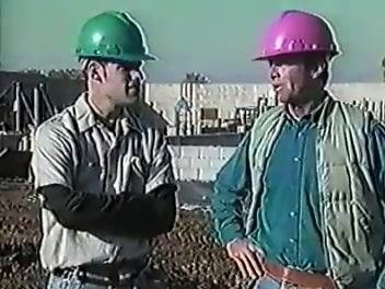 The two workers in green and pink hard hats standing together, concluding the safety discussion.