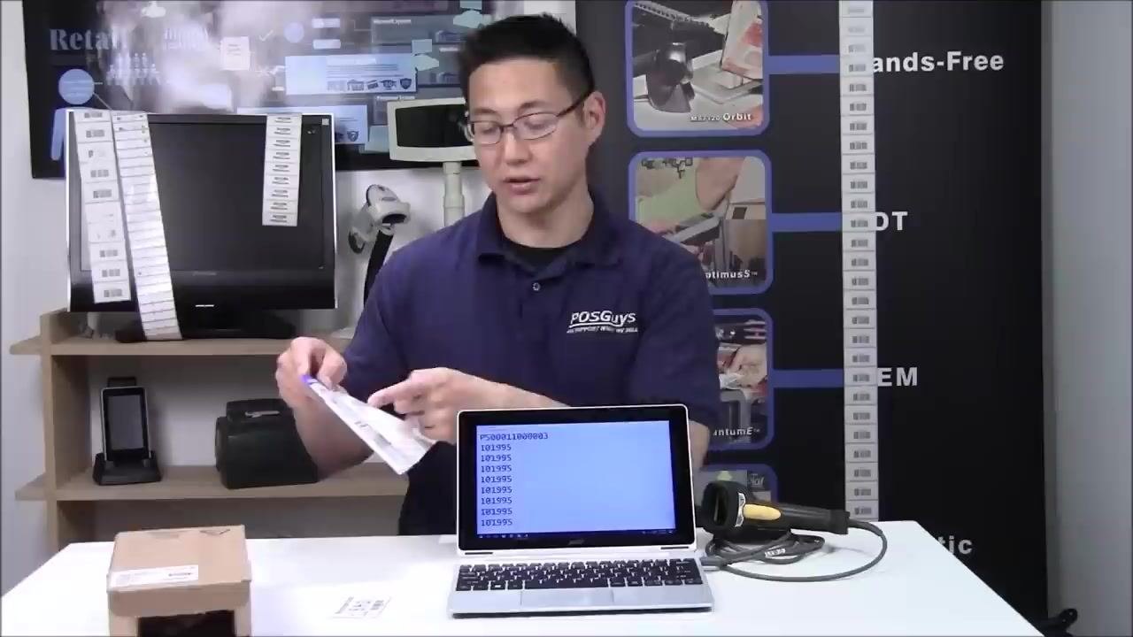 A person pointing to the quick start guide, demonstrating the reset process, with the scanner on the table next to the laptop.