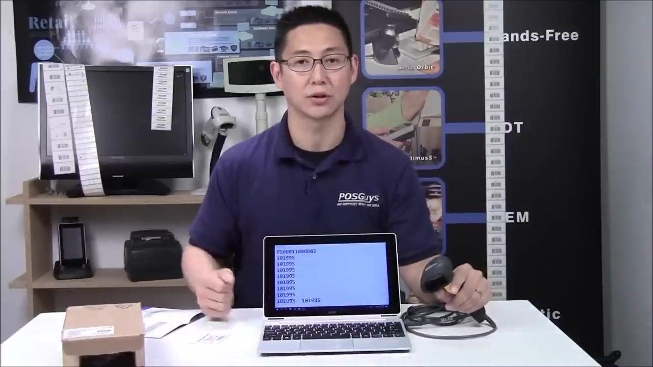 A person sitting at the table with the scanner and laptop, confirming the scanner's configuration, with the quick start guide open on the table.