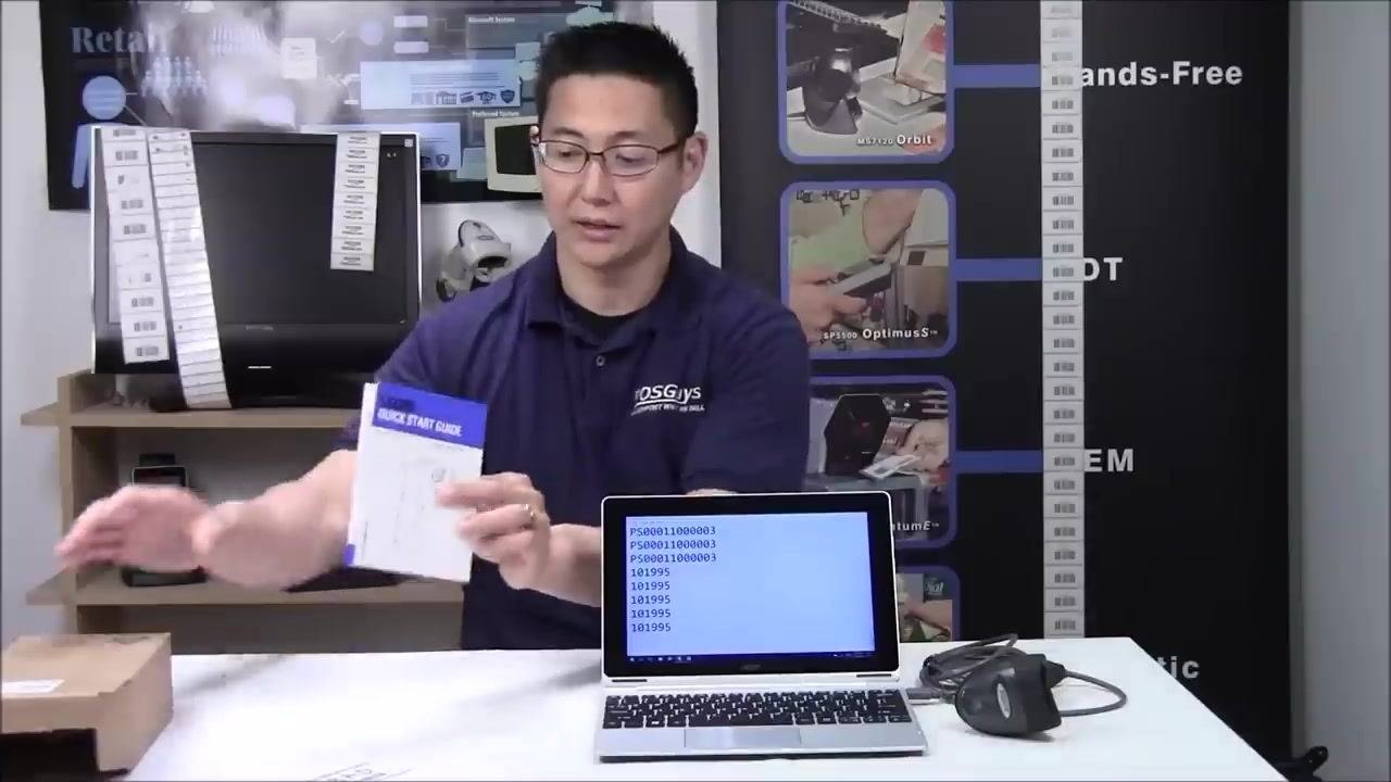 A person holding up a document labeled "Quick Start Guide," with the laptop and scanner on the table.