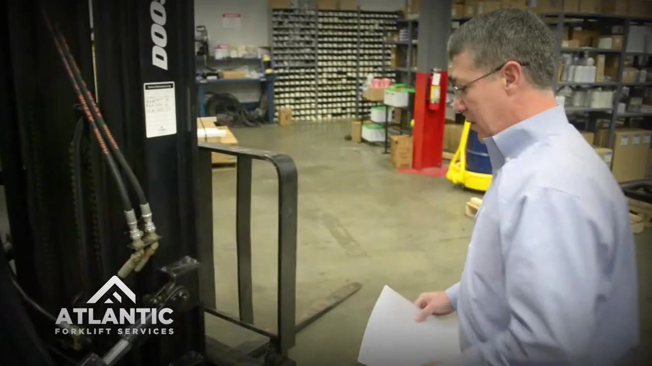 Inspector visually checking the overhead guard and lights above the operator's seat on the forklift.