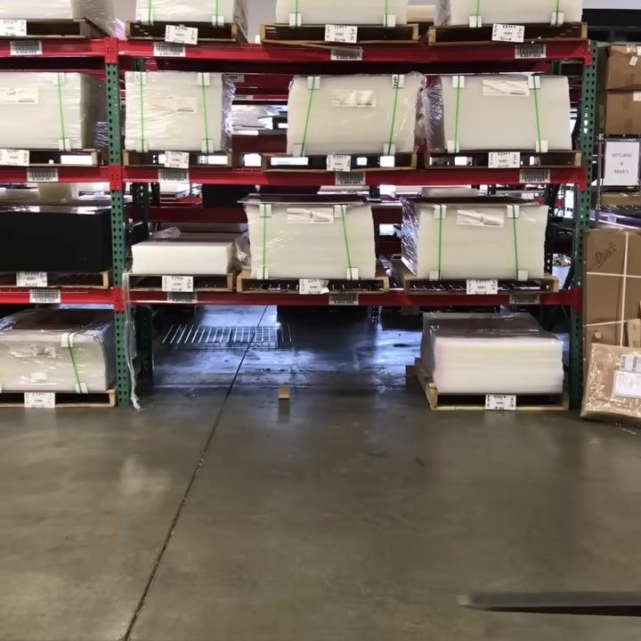 Warehouse with pallet racks, stacked goods, and clear aisles. No forklift visible yet.