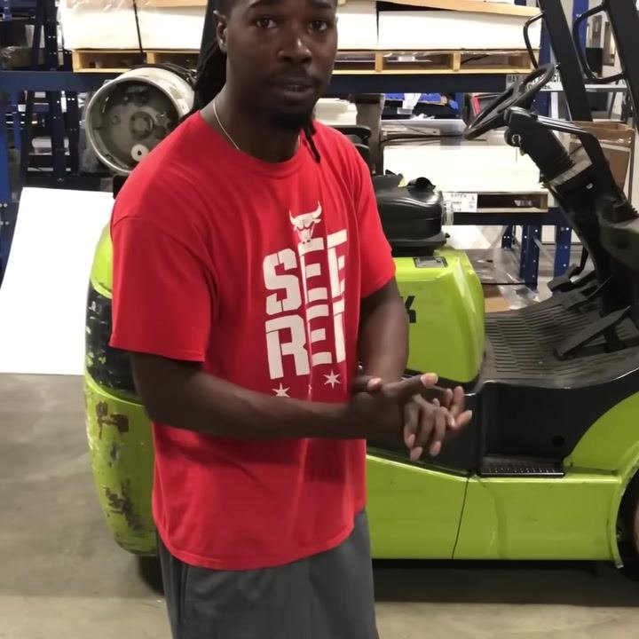 Operator facing the camera, hands together, giving safety advice about taking your time when operating the forklift.