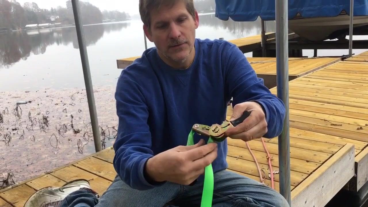 The ratchet strap wound tightly around the barrel, with the dock and lake visible in the background.