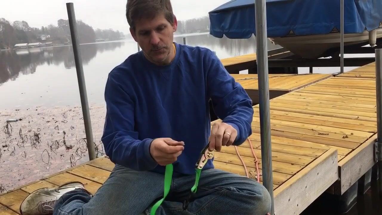 A hand pulling the single release lever on the ratchet with one finger, loosening the strap from the barrel.