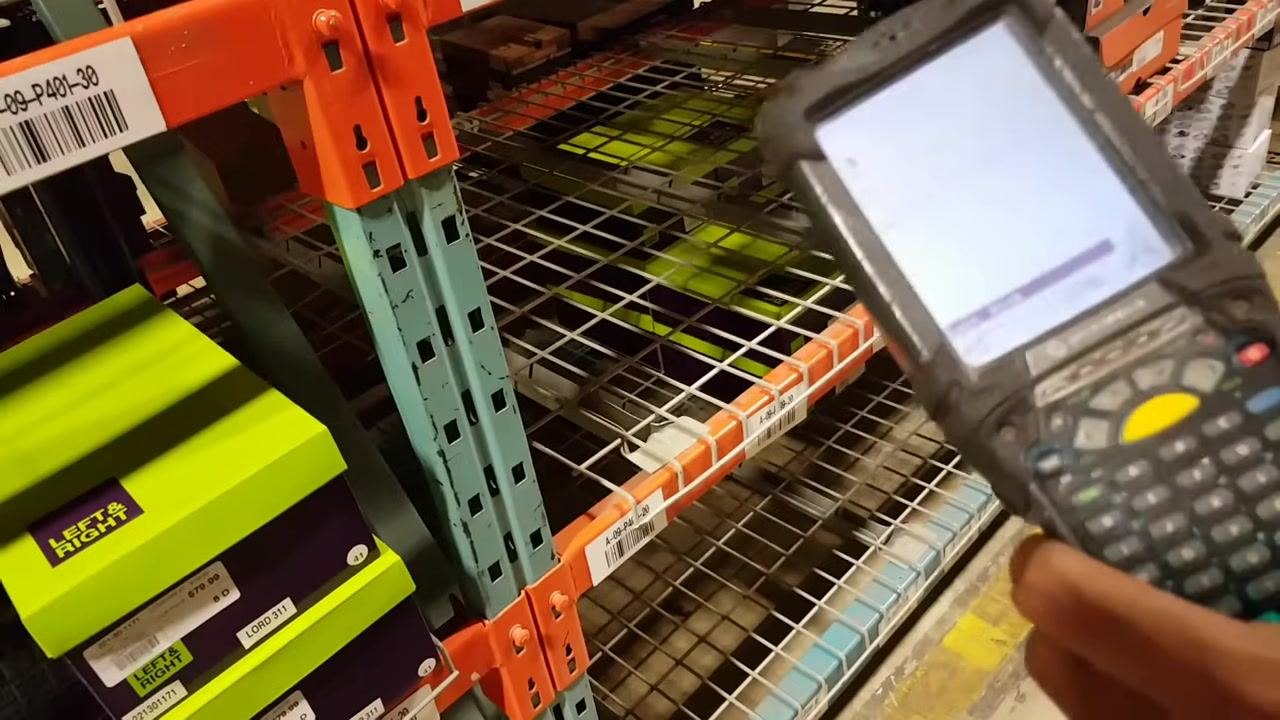Close-up of a person entering data on a Motorola handheld scanner, with a green "LEFT & RIGHT" shoe box nearby.