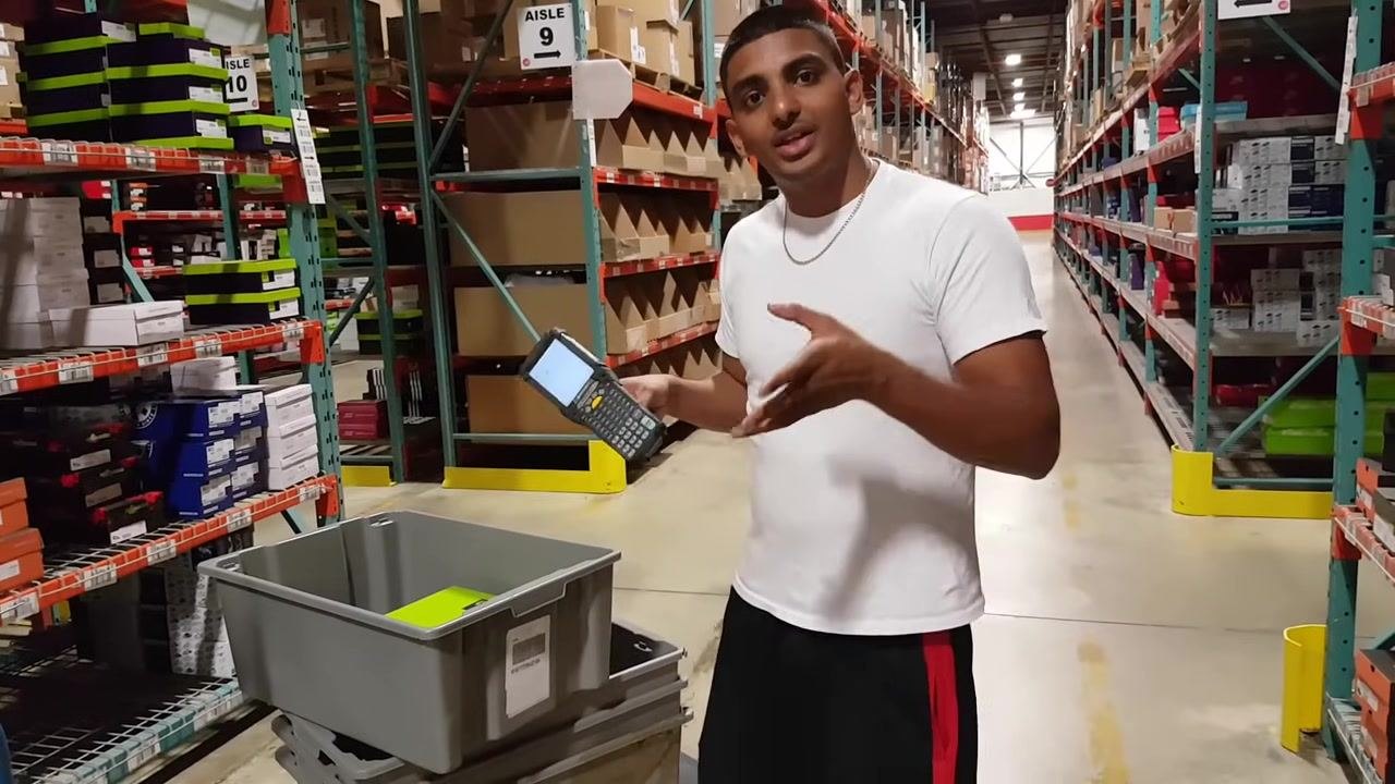 Person in a white shirt places a green "LEFT & RIGHT" shoe box into a gray tote in the warehouse aisle.